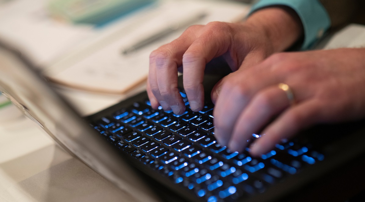 A person typing on a black laptop's keyboard